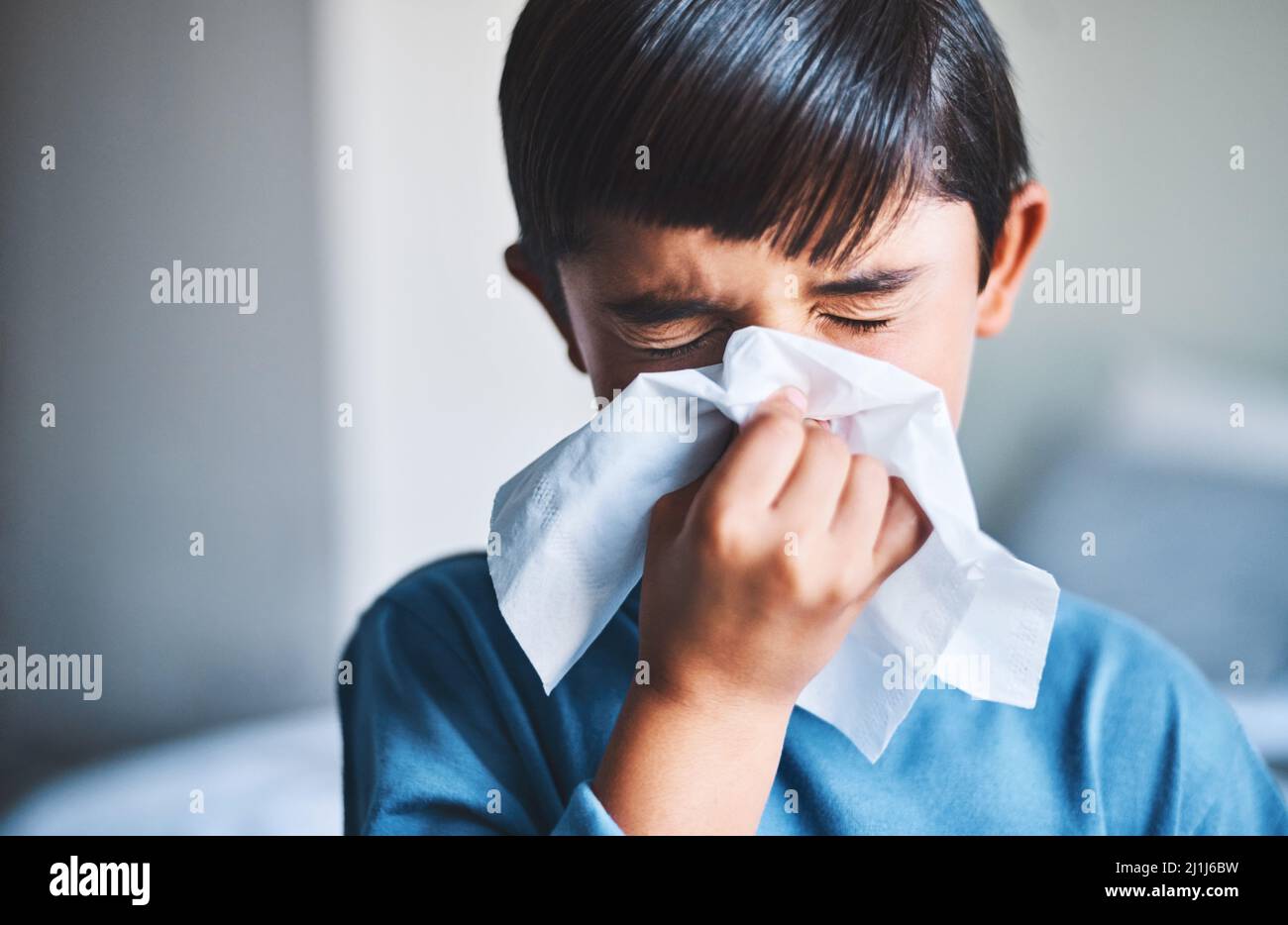 Ah-choo. Scatto corto di un adorabile ragazzino che gli soffia il naso mentre si trova in casa. Foto Stock