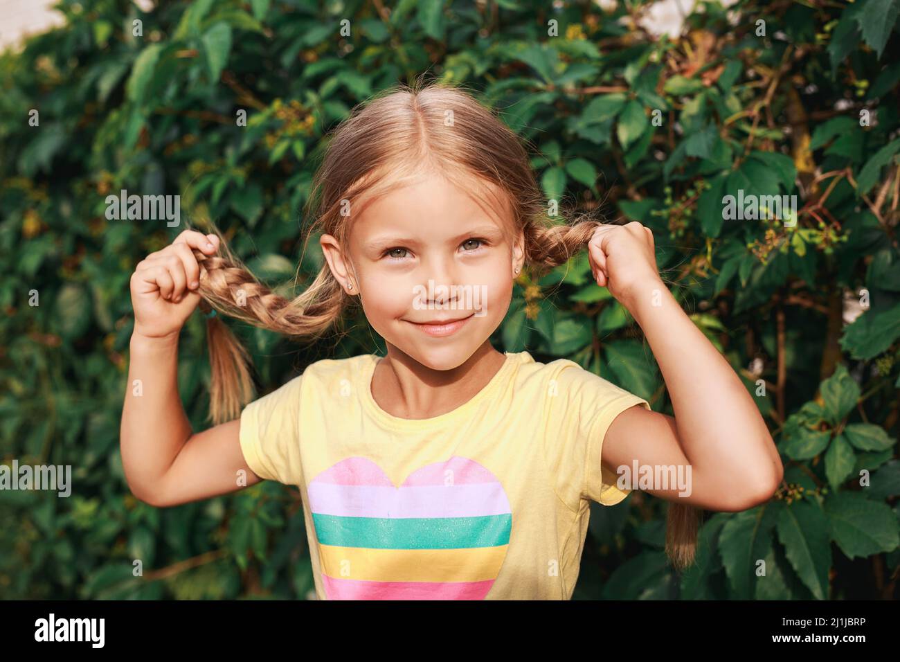 Primo piano ritratto di ragazza divertente con pigtail all'aperto. Vacanze estive Foto Stock