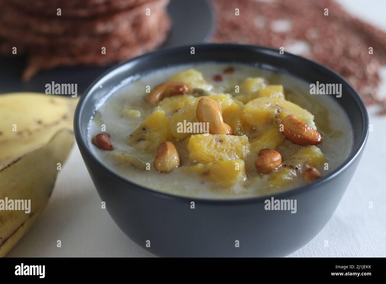 Stufato di piantina maturo. Un curry dolce fatto di plantain maturo, latte di cocco e condito con anacardi arrostiti. Servito con frittelle di riso rosso. Una versione di K Foto Stock