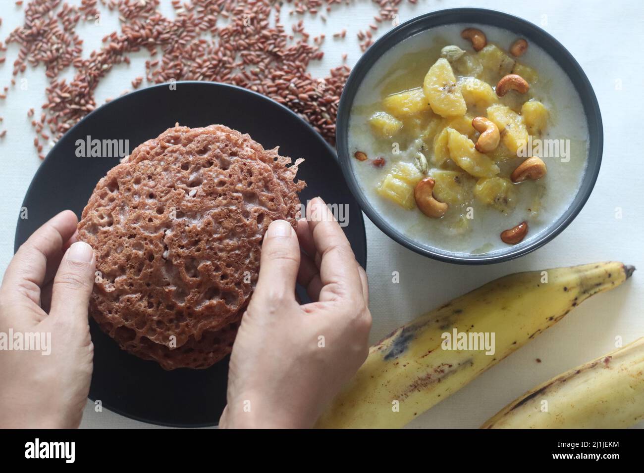 Frittelle di riso rosso. Frittelle fatte di una pastella fermentata di riso rosso e cocco. Chiamato anche appam di riso rosso in Kerala. Servito con stufato di piantina maturo. Foto Stock