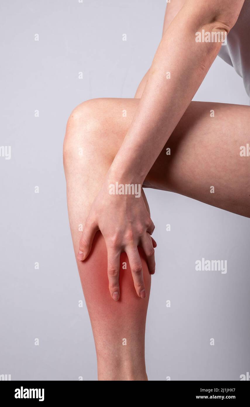 Donna massaggiante polpaccio doloroso per le gambe con punto rosso primo piano. Lesioni alle articolazioni. Concetto di problemi di salute. Foto di alta qualità Foto Stock