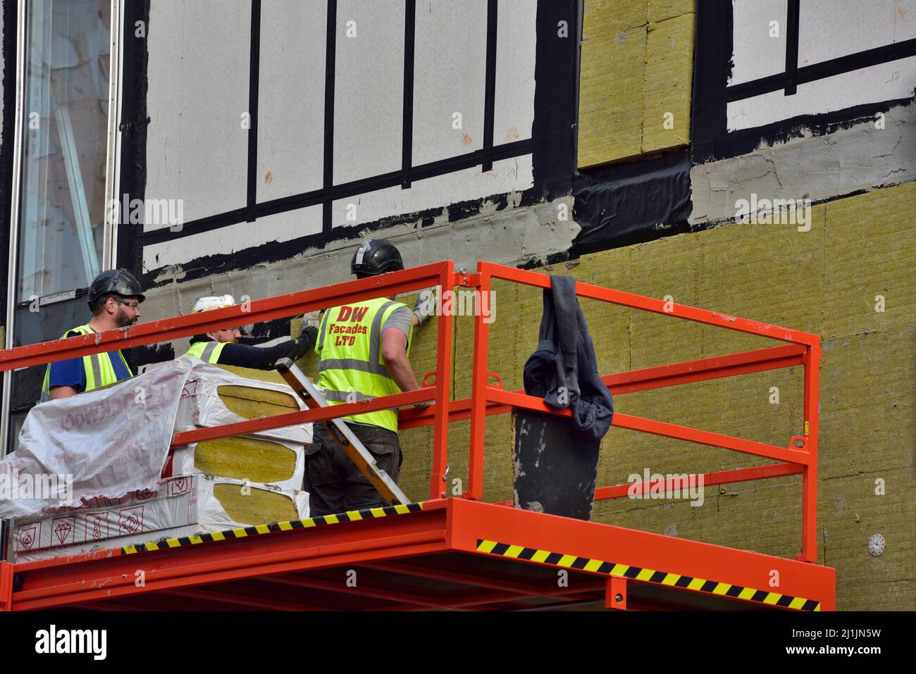 Pannello isolante esterno in lana di roccia installato sulla facciata del nuovo edificio da una piattaforma di sollevamento a forbice Foto Stock