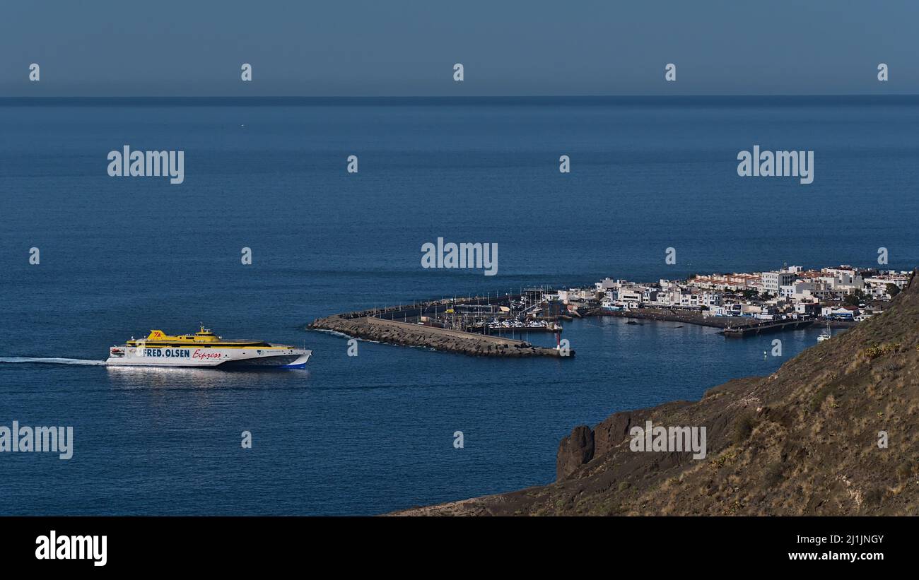 Vista di Port Puerto de las Nieves sulla costa nord-occidentale dell'isola di Gran Canaria, Spagna con l'avvicinarsi di Fred. Traghetto Olsen Express. Foto Stock