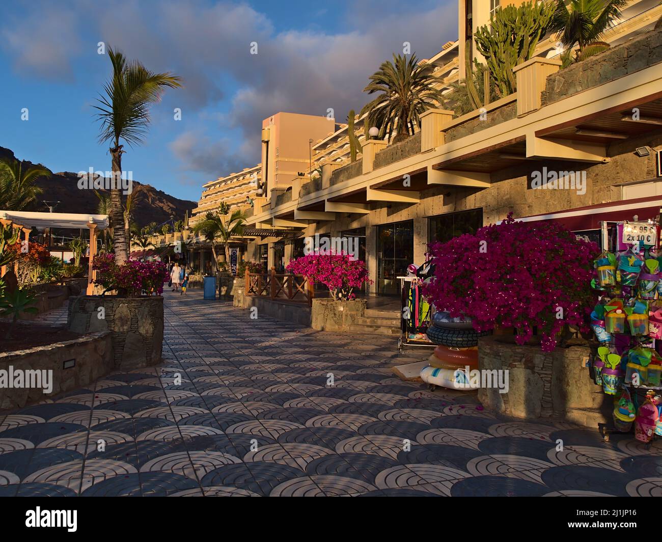 Vista sul lungomare con negozi di fronte al famoso Hotel Paradise Lago Taurito nel sud di Gran Canaria, Spagna in serata luce del sole con fiori. Foto Stock
