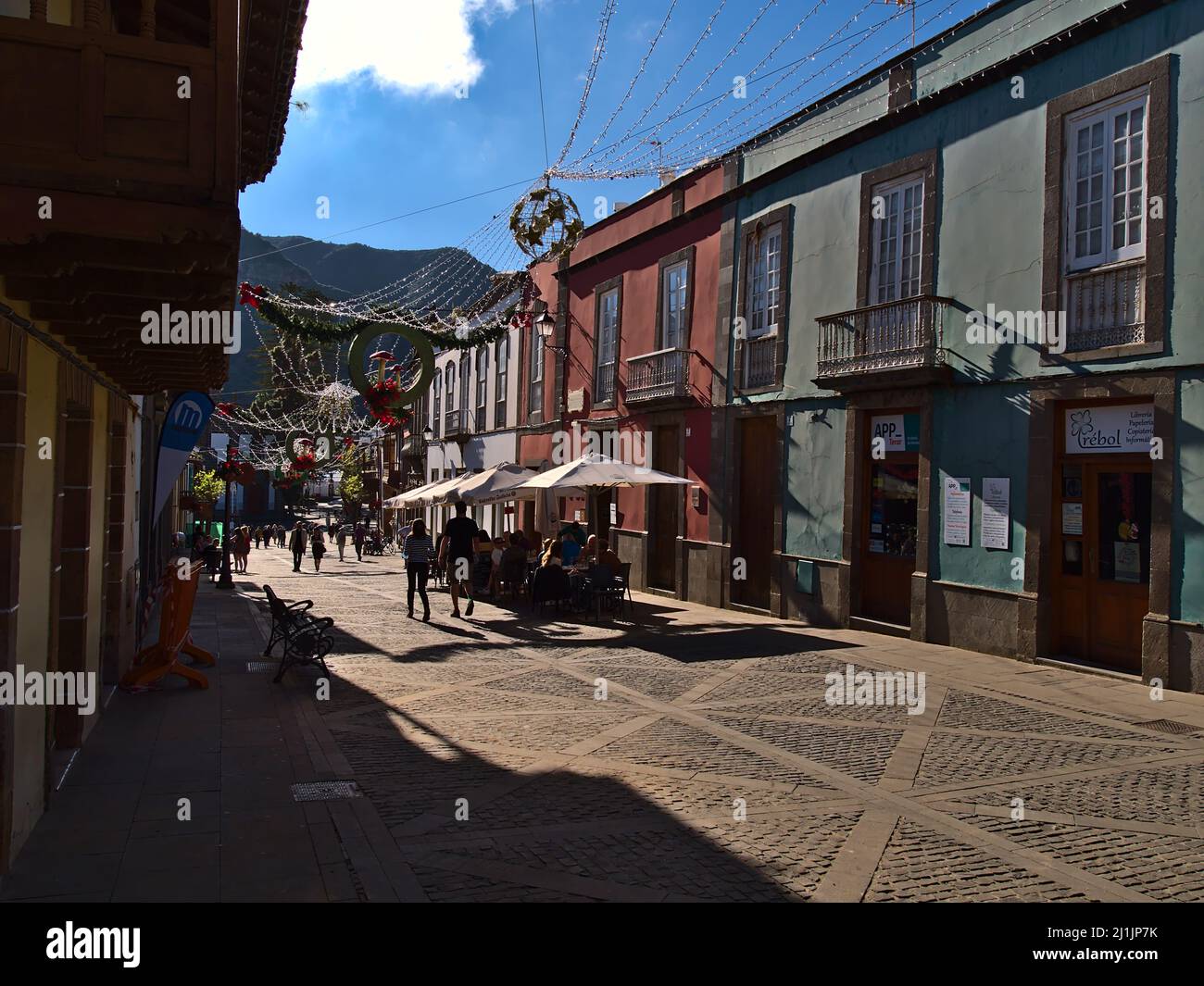 I turisti si godono il sole pomeridiano nella zona pedonale della cittadina di Teror, Gran Canaria, Spagna con edifici storici e decorazioni natalizie. Foto Stock