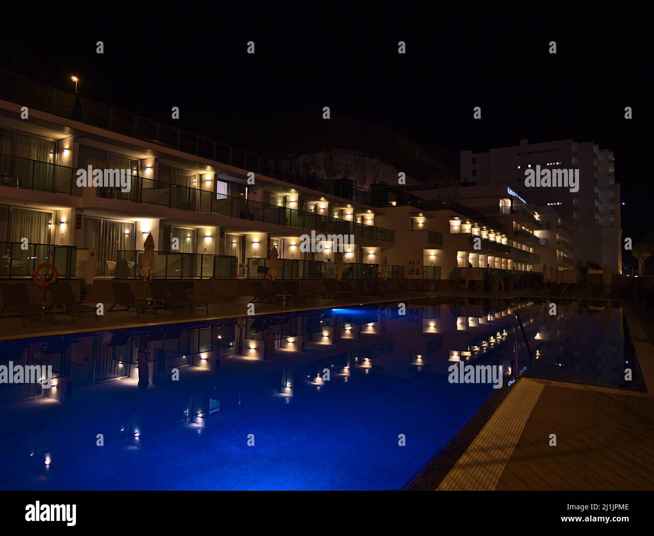 Vista della scintillante piscina blu del resort di vacanza a Puerto Rico, Gran Canaria meridionale, Spagna di notte con le luci riflesse nell'acqua. Foto Stock