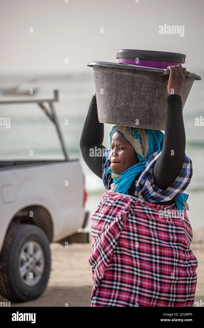 Una donna nera che porta grandi bacini sulla sua testa, Nouakchott mercato del pesce, Mauritania Foto Stock