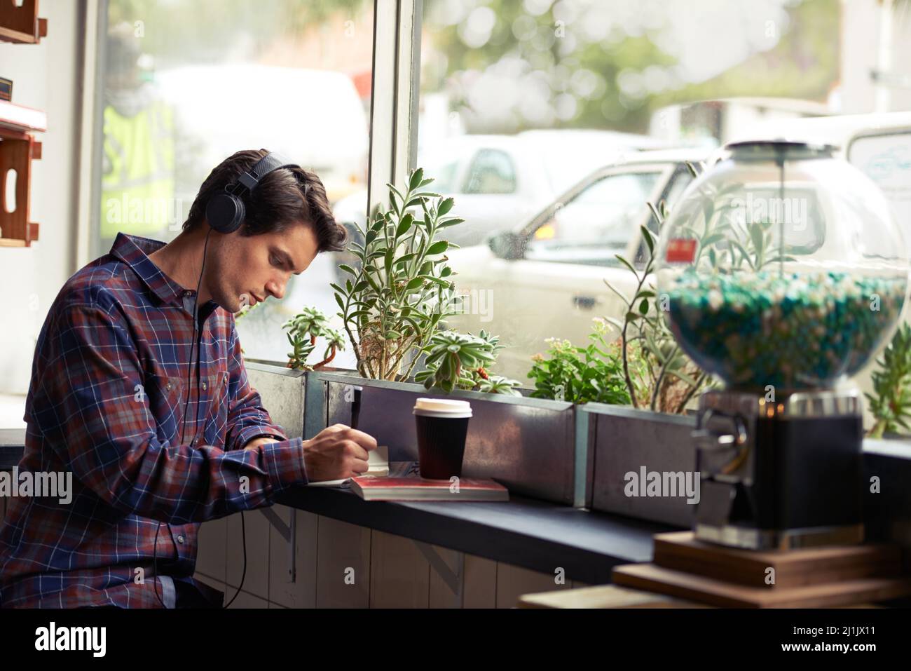 Hipster al lavoro. Scatto di un giovane che studia in un bar e ascolta musica. Foto Stock