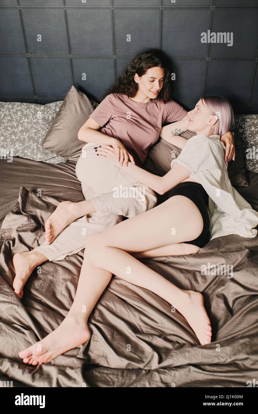 Felice attraente giovane lesbiche caucasiche in sleepwear guardando altri rach mentre si sveglia insieme Foto Stock