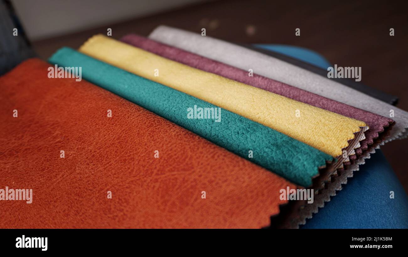 Primo piano, campioni di tessuto colorato per tappezzeria su sfondo blu. Esempio di catalogo tessuti. Messa a fuoco selettiva. Foto Stock