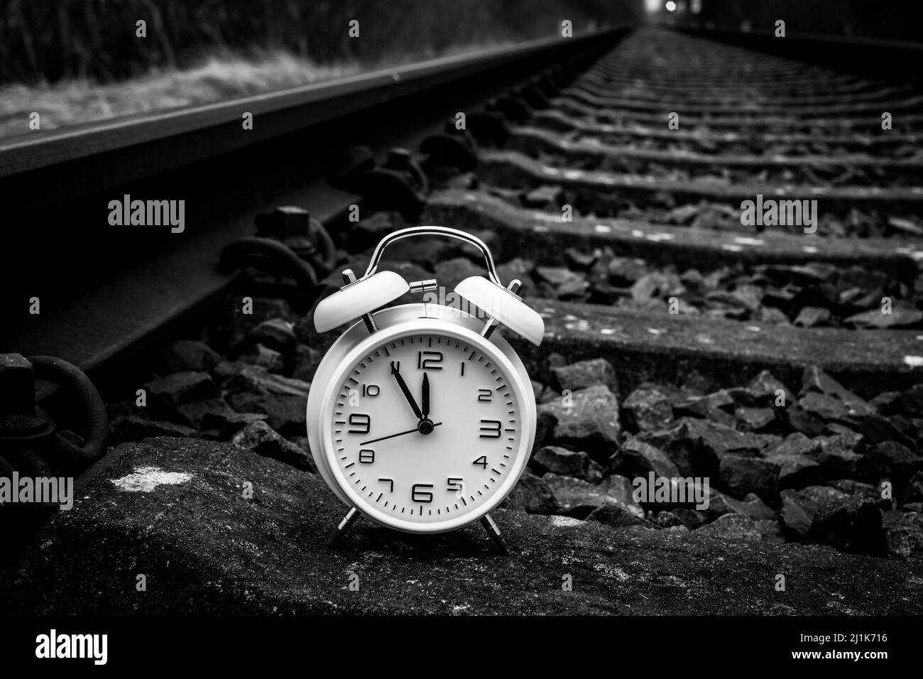 sulle rotaie della ferrovia si trova una classica sveglia bianca con i tempi da 5 a 12 Foto Stock