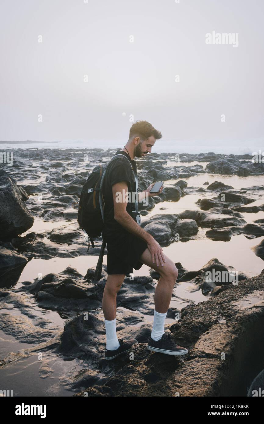 Giovane uomo che usa il cellulare su una spiaggia Foto Stock