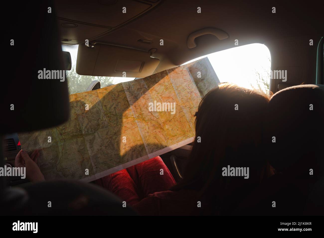 Ragazza che guarda e indica una mappa durante un viaggio su strada Foto Stock