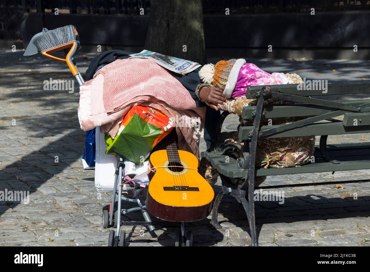 La persona senza tetto dorme accanto al banco del parco a East Village NYC. Foto Stock