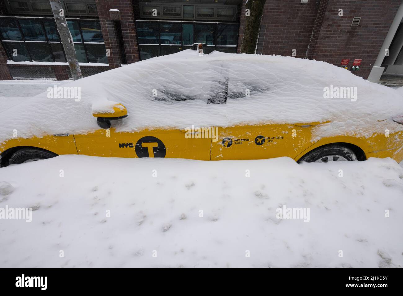 Snow avvolge un taxi giallo sulla strada a East Village NYC Foto Stock