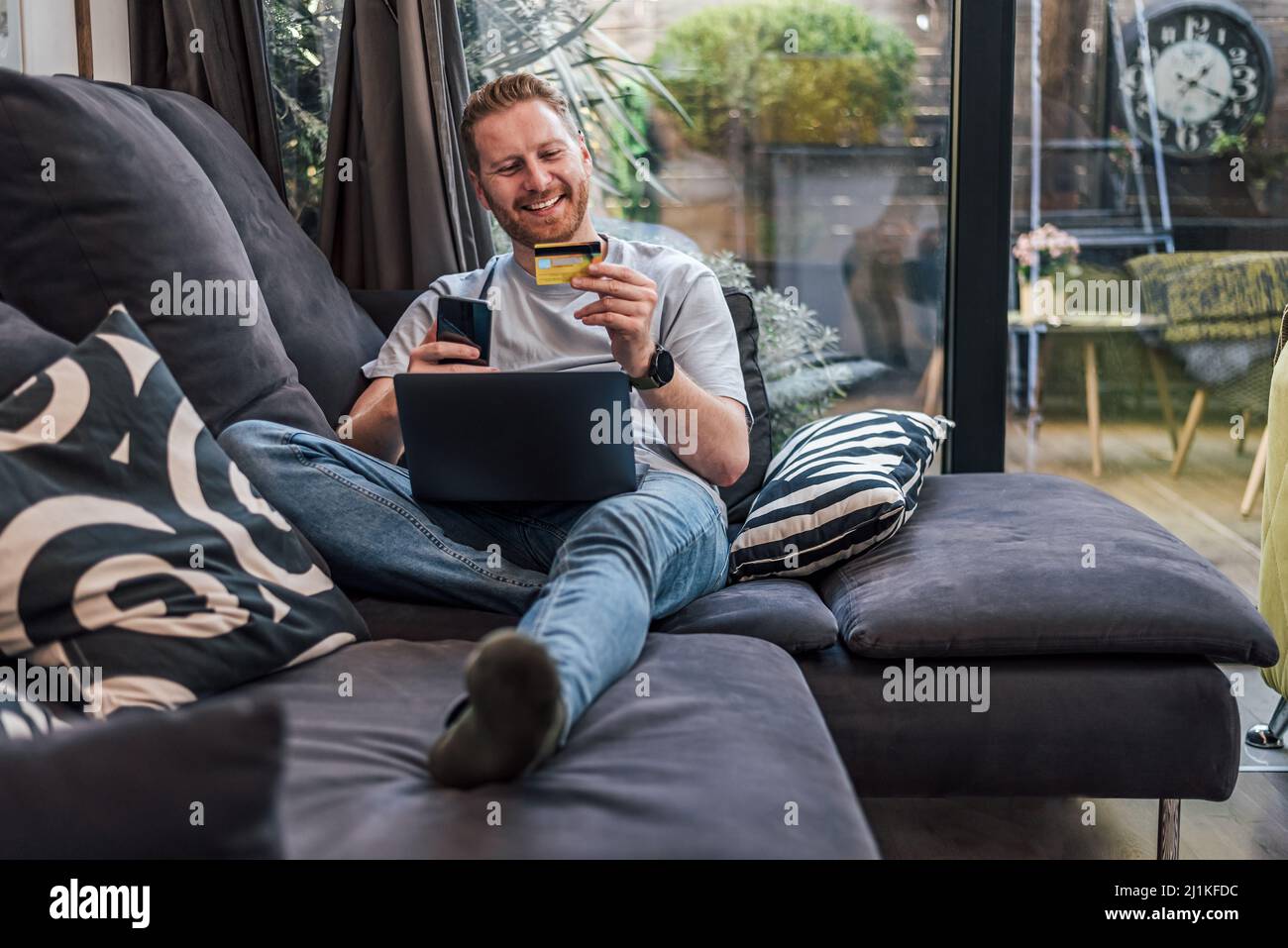 Uomo adulto allegro, guardando il suo numero di carta di credito e la password, online. Foto Stock