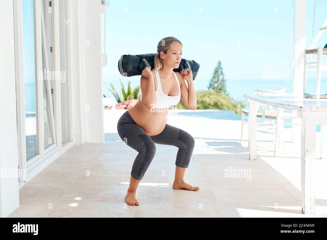 Alzando il suo senso ad una gravidanza forte. Shot di una donna incinta che si sta allenando con una borsa di sabbia sul patio a casa. Foto Stock