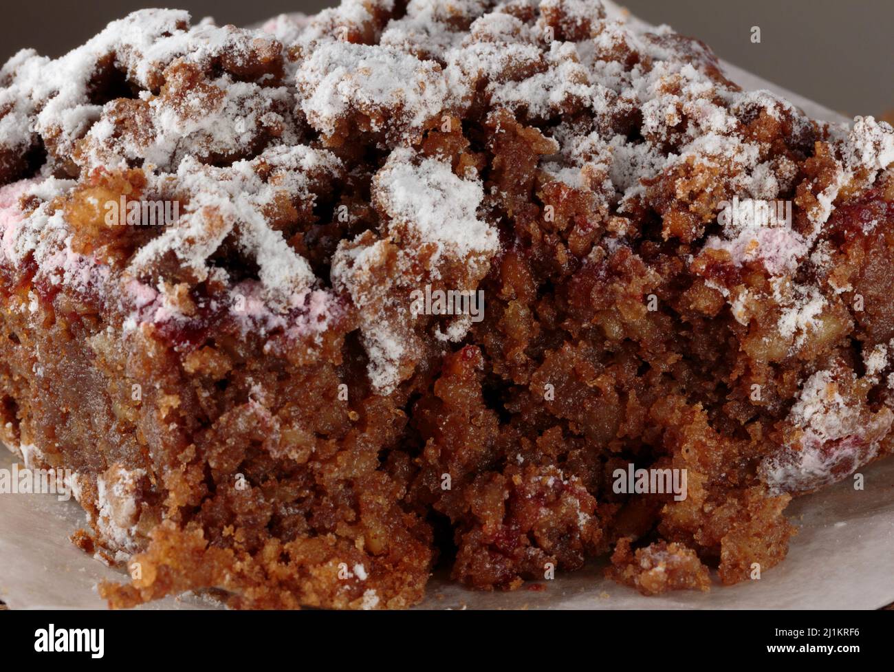 primo piano, macrosolato di un pezzo di torta grattugiata di carota rasberry cosparso di zucchero in polvere, l'interno chiaramente visibile dopo essere stato tagliato in Foto Stock
