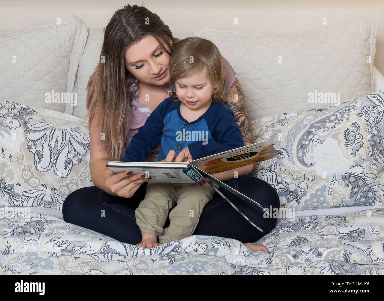 Bella mamma giovane che legge con il suo bambino Foto Stock