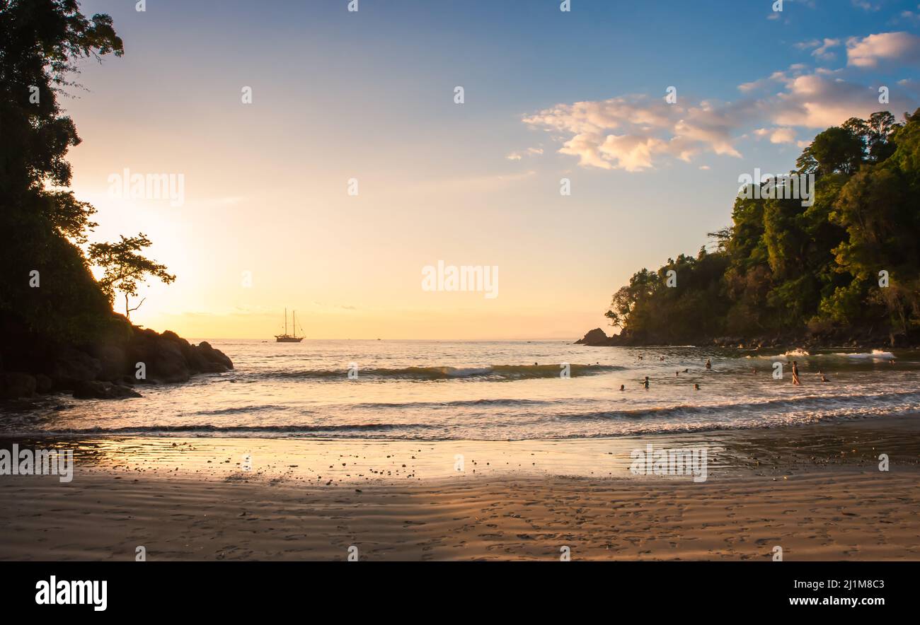 Scena di spiaggia con la gente nell'oceano al tramonto in Costa Rica. Foto Stock