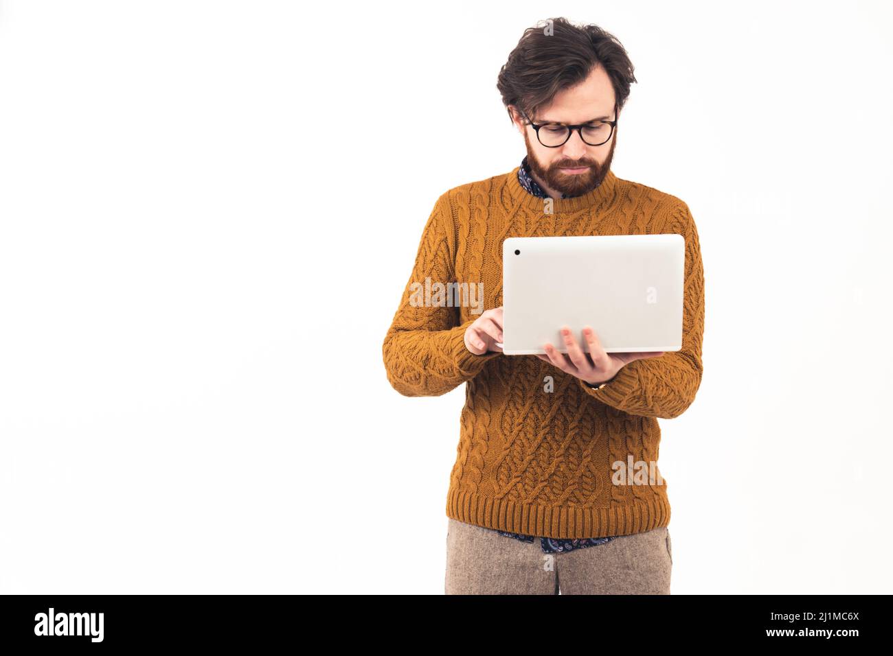Medio scatto giovane buon-osservante bearded concentrato uomo caucasico in piedi, usando il suo laptop guardando lo schermo hipster remoto lavoro online apprendimento concetto bianco sfondo copia spazio isolato studio shot . Foto di alta qualità Foto Stock