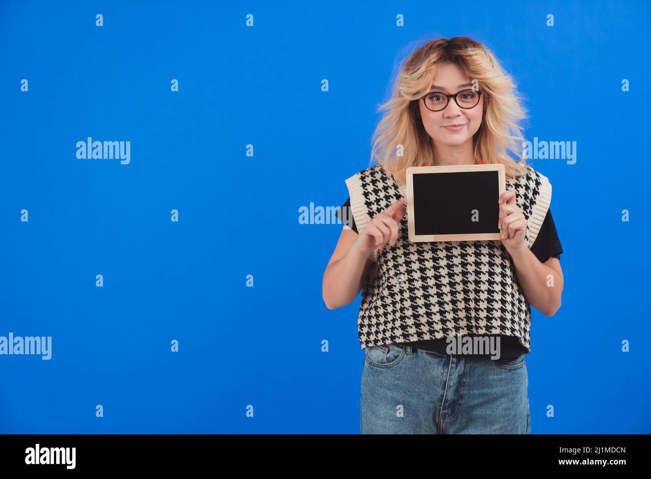 Bella donna caucasica indossare occhiali e tenere tablet o lavagna a macchina fotografica. Spazio di copia. Isolato. Sfondo blu. . Foto di alta qualità Foto Stock