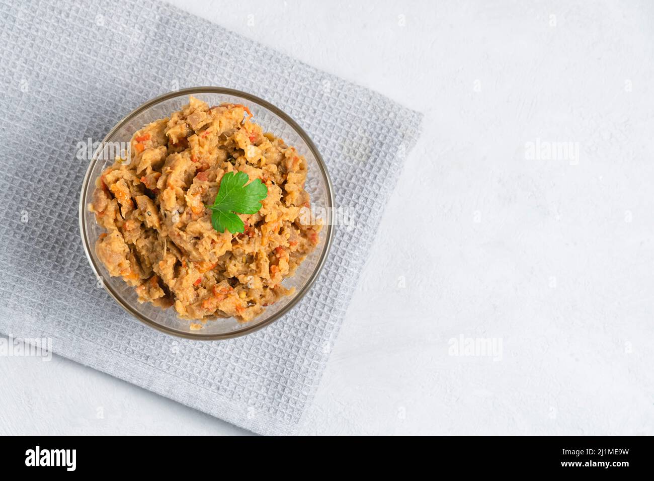 Vista dall'alto del tradizionale piatto balcanico Kiopoolu, a base di melanzane sparse in una ciotola di vetro su sfondo grigio con spazio copia Foto Stock