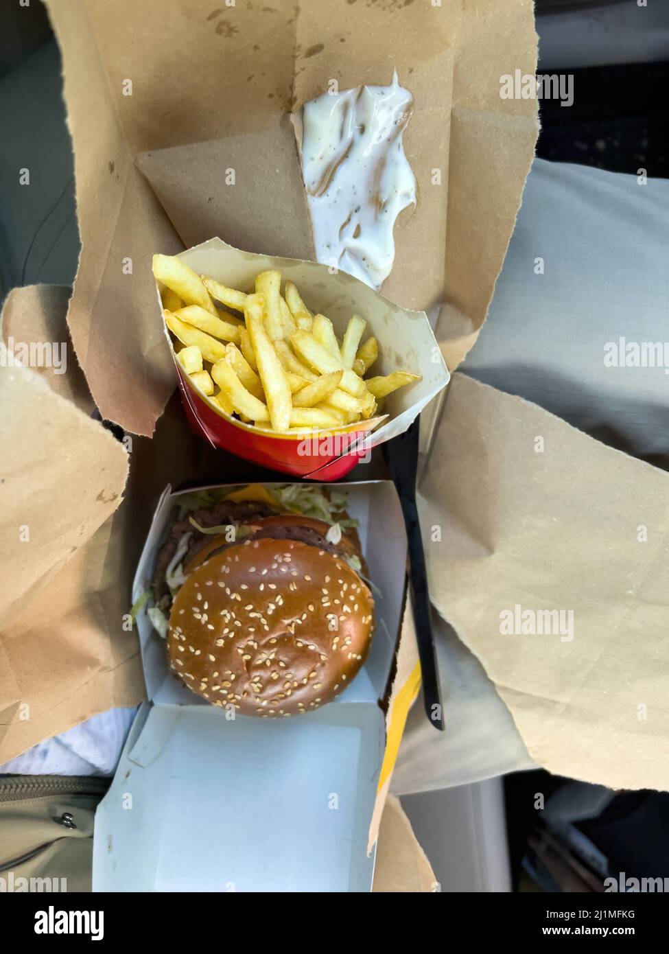 Basilea, Svizzera - 20 dicembre 2021: Vista dall'alto sulle ginocchia delle deliziose patatine fritte e degli hamburger tripli acquistati dal ristorante McDonalds Basel Foto Stock