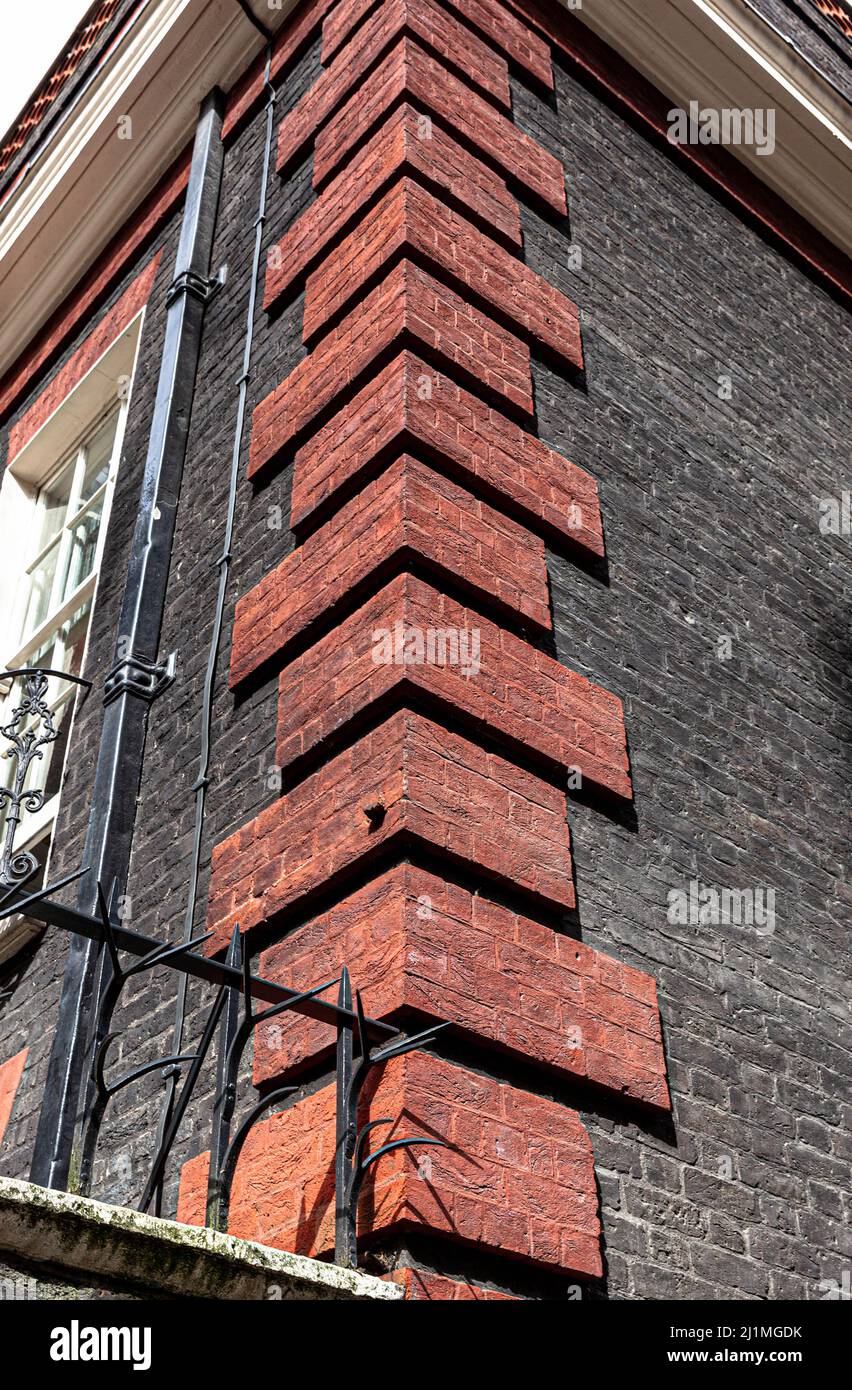 Vista ad angolo basso di un angolo decorato con quoini di mattoni rossi, Londra, Inghilterra, Regno Unito. Foto Stock