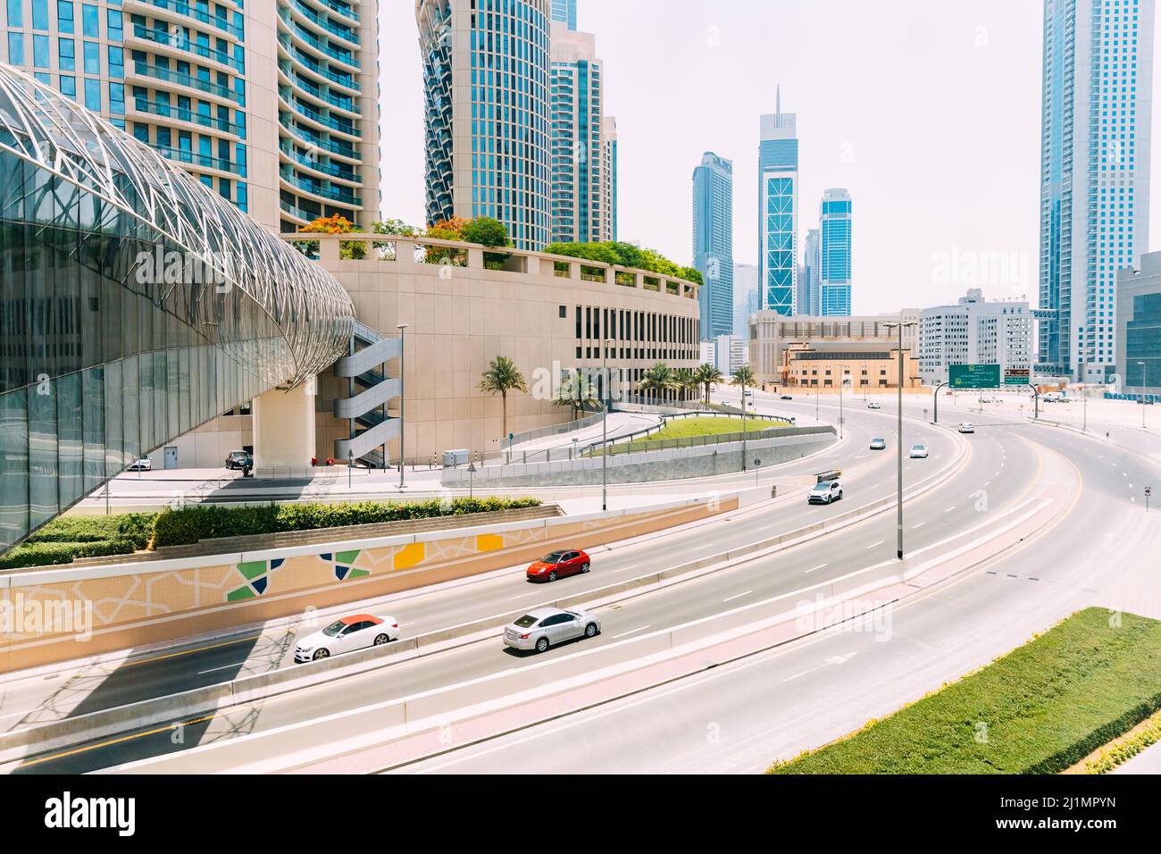 Auto che si spostano su strada tra grattacieli di vetro a Dubai. Traffico in strada a Dubai. Auto in movimento in strada. Moderno con architettura grattacieli di Foto Stock