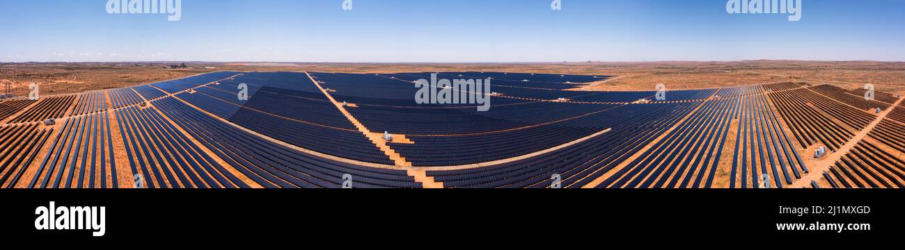 Enorme centrale elettrica rinnovabile pannelli solari a rotta collina mineraria città di Outback australiano - ampio panorama aereo. Foto Stock