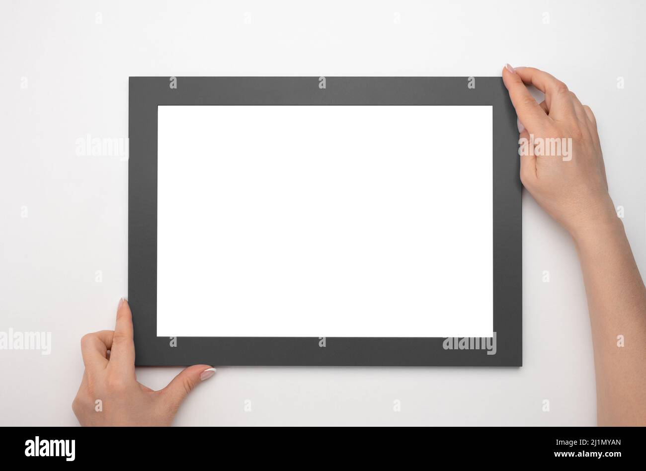 Telaio di supporto. Foto Mockup. Le mani della donna tengono il telaio nero. Per il design di cornici e poster. Dimensioni del telaio A4. Isolato su sfondo bianco. Bianco ph Foto Stock