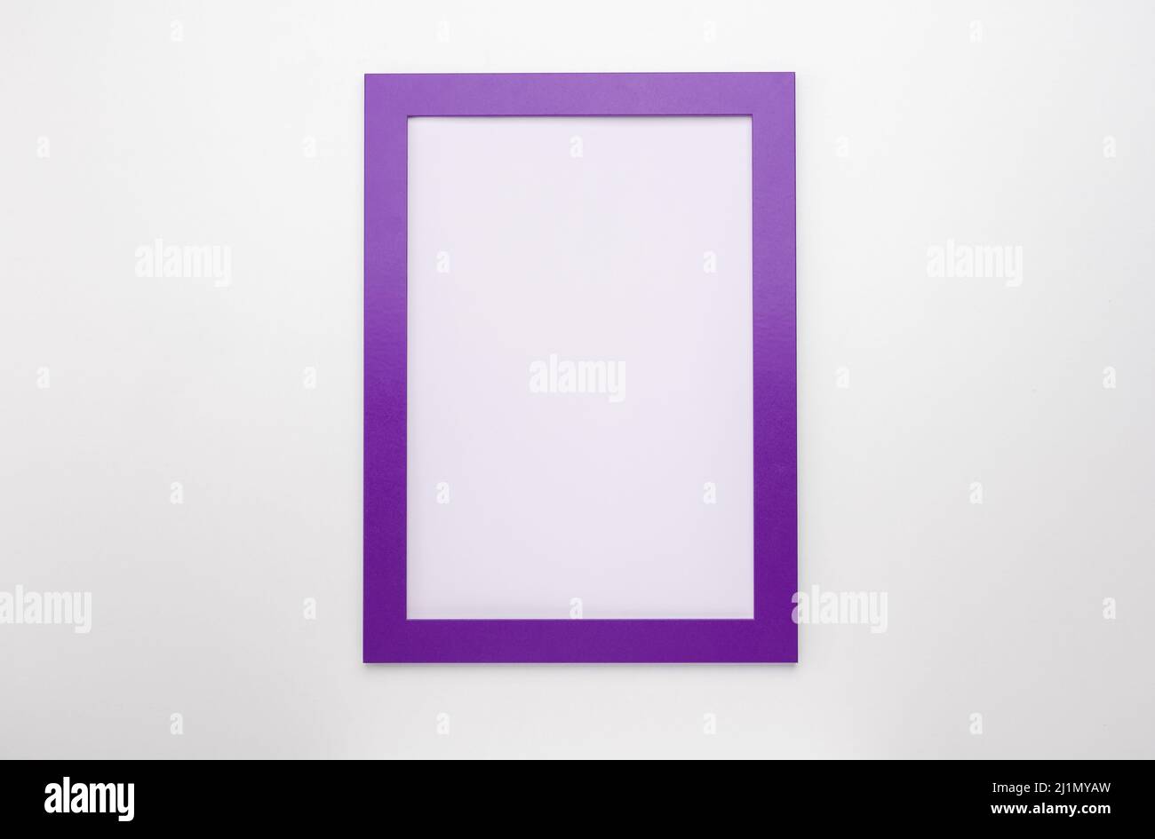 cornice fotografica verticale mockup su parete bianca. cornice diploma viola bianca su sfondo bianco. Cornice mockup. Cornice diploma vuota su parete bianca Foto Stock