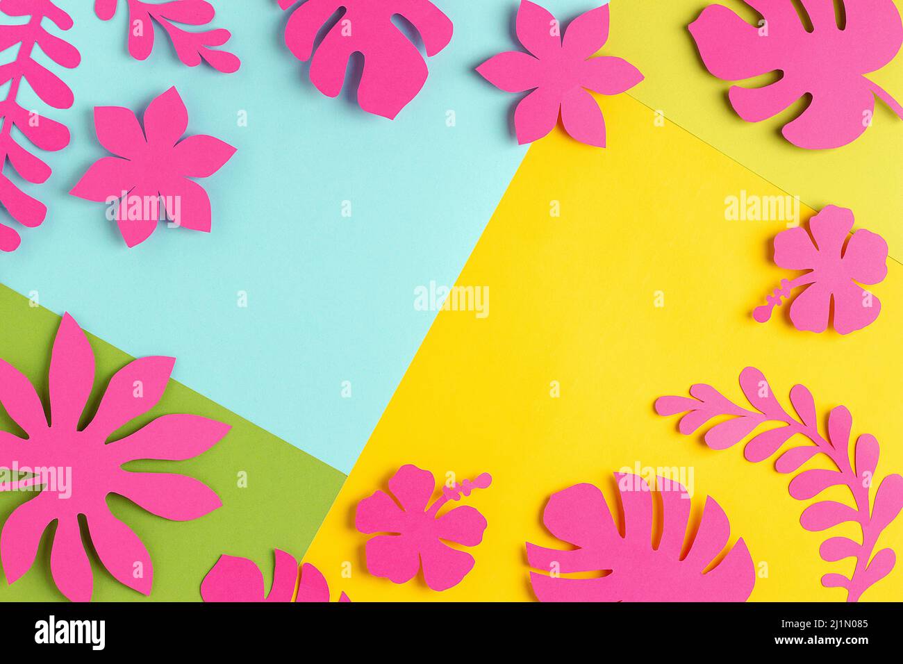 Cornice tropicale alla luce del sole di tendenza realizzata con fiori di carta rosa brillante e foglie su sfondo giallo blu, come sfondo o texture. Bordo floreale per te Foto Stock