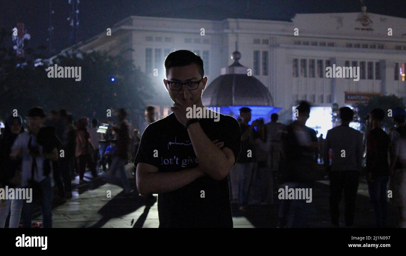 Jakarta, Indonesia - 01 03 2021: Un uomo con vetri in piedi di fronte ad una zona turistica di Kota Tua Jakarta di notte Foto Stock