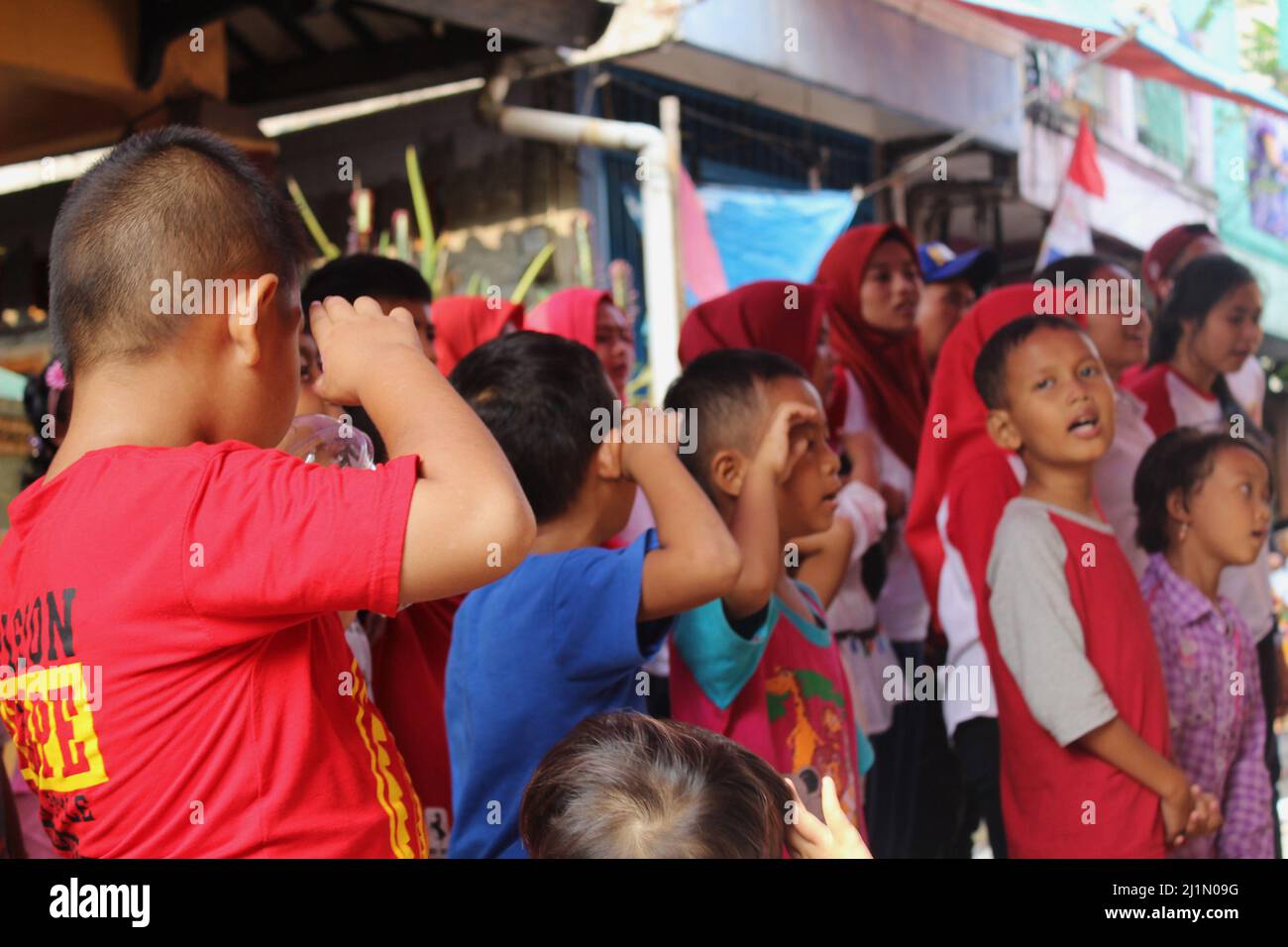 Jakarta, Indonesia - 01 03 2021: Bambini che sono rispettosi mentre partecipano alla cerimonia di indipendenza indonesiana 72nd su una strada nel Jakart Foto Stock