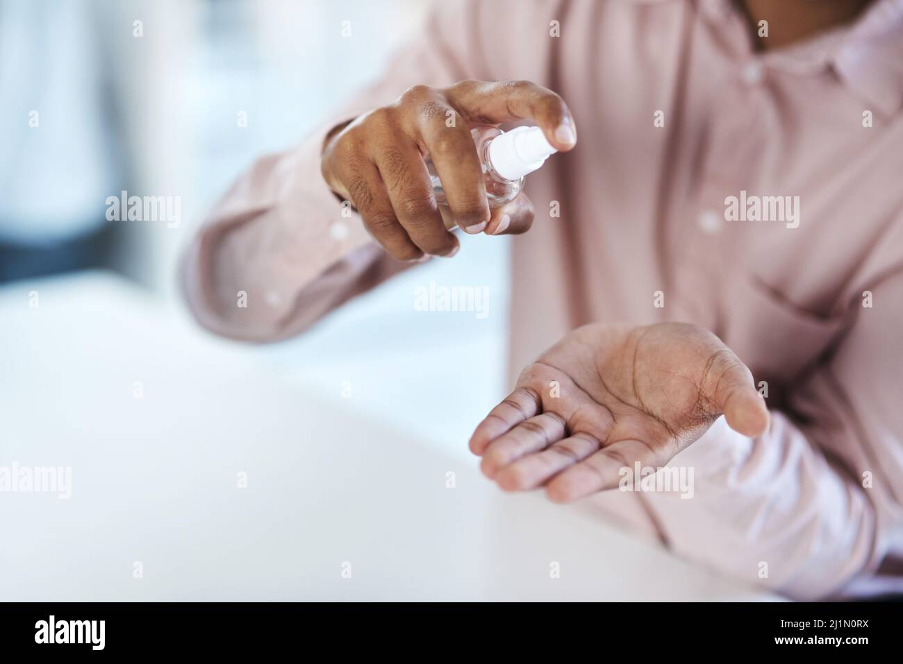 I germi possono sembrare invisibili, ma ci sono. Primo piano di un uomo d'affari irriconoscibile che utilizza igienizzatore a mano in un ufficio. Foto Stock