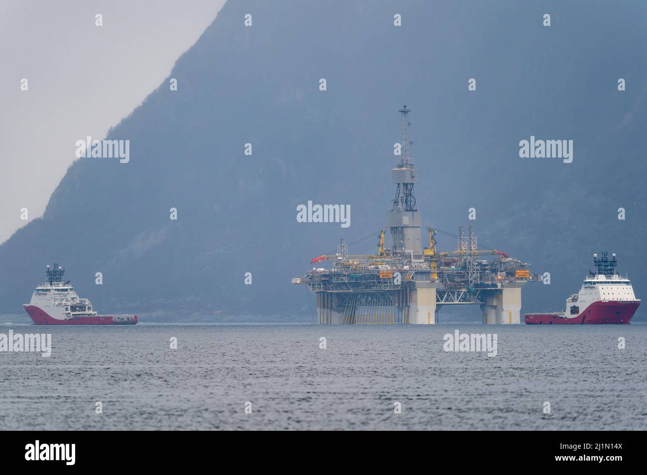 RIG spostamento della piattaforma petrolifera di Equinor Njord Alpha con ahts vasi Siem Pearl e Siem Opal all'interno del fiordo norvegese. Foto Stock