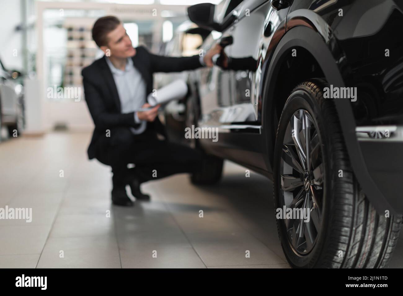 Giovane responsabile vendite prendere appunti mentre si controlla la nuova automobile al salone di lusso auto, fuoco selettivo Foto Stock