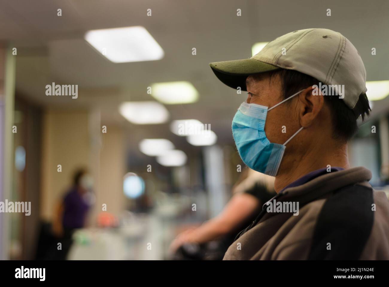 Persone che indossano la maschera per il viso e in attesa presso la clinica per la vaccinazione del coronavirus. Persone che si siedono a 2 metri di distanza, Auckland. Foto Stock