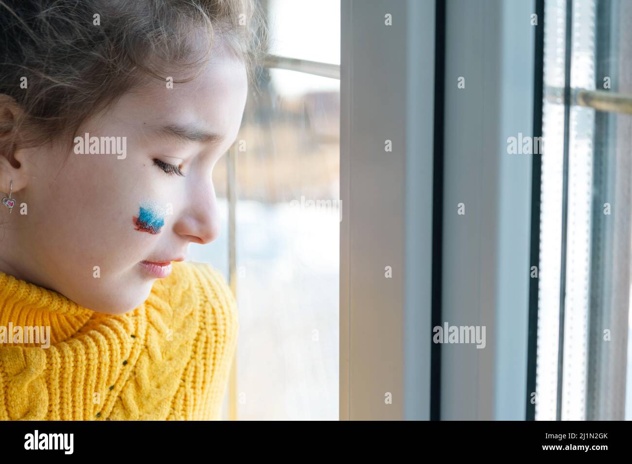 Un bambino triste alla finestra con la bandiera della Russia, si preoccupa di lacrime nei suoi occhi. Conflitto tra Russia e Ucraina, paura Foto Stock