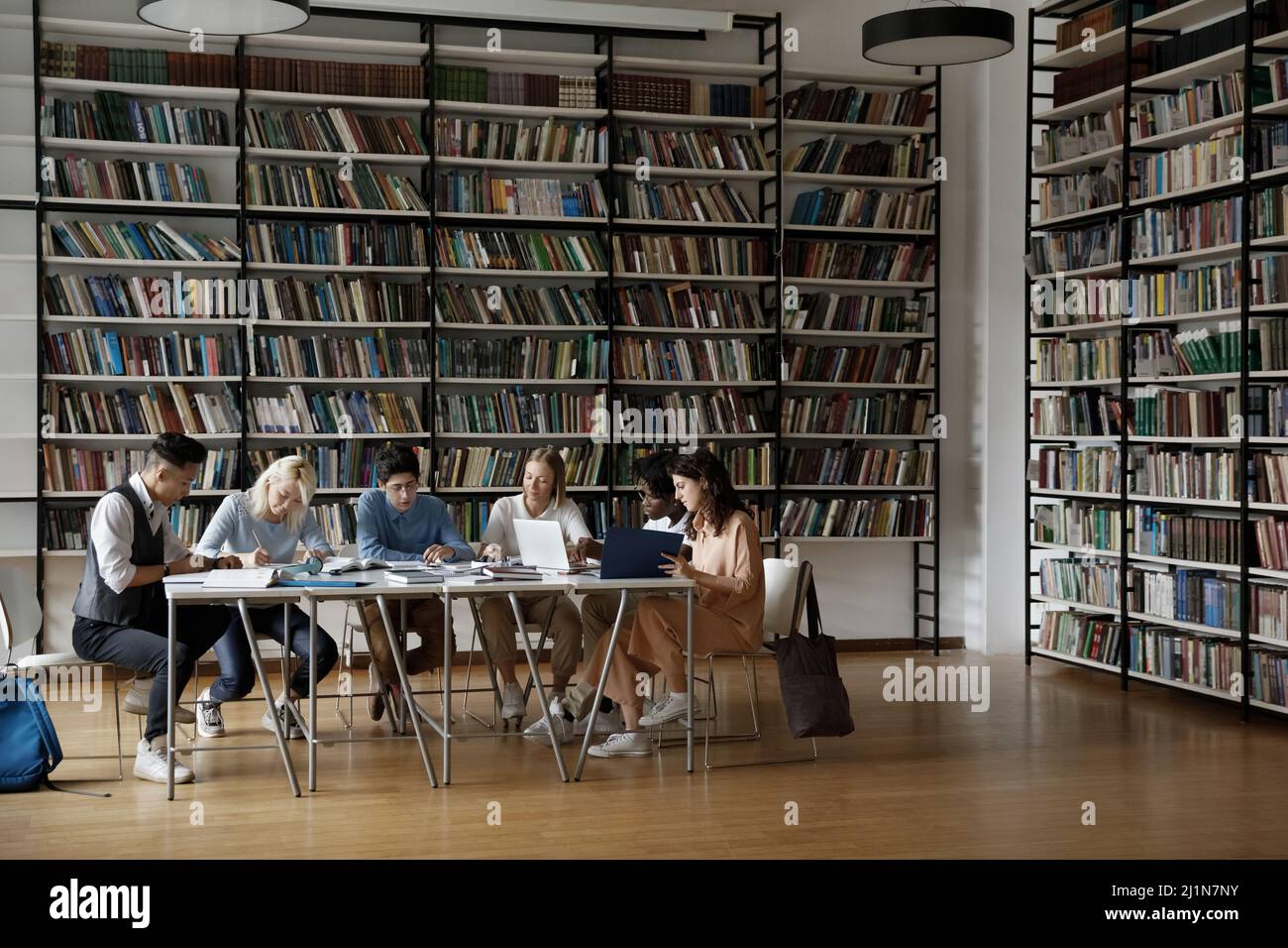 Gruppo di studenti multirazziali seduti a tavola in biblioteca Foto Stock
