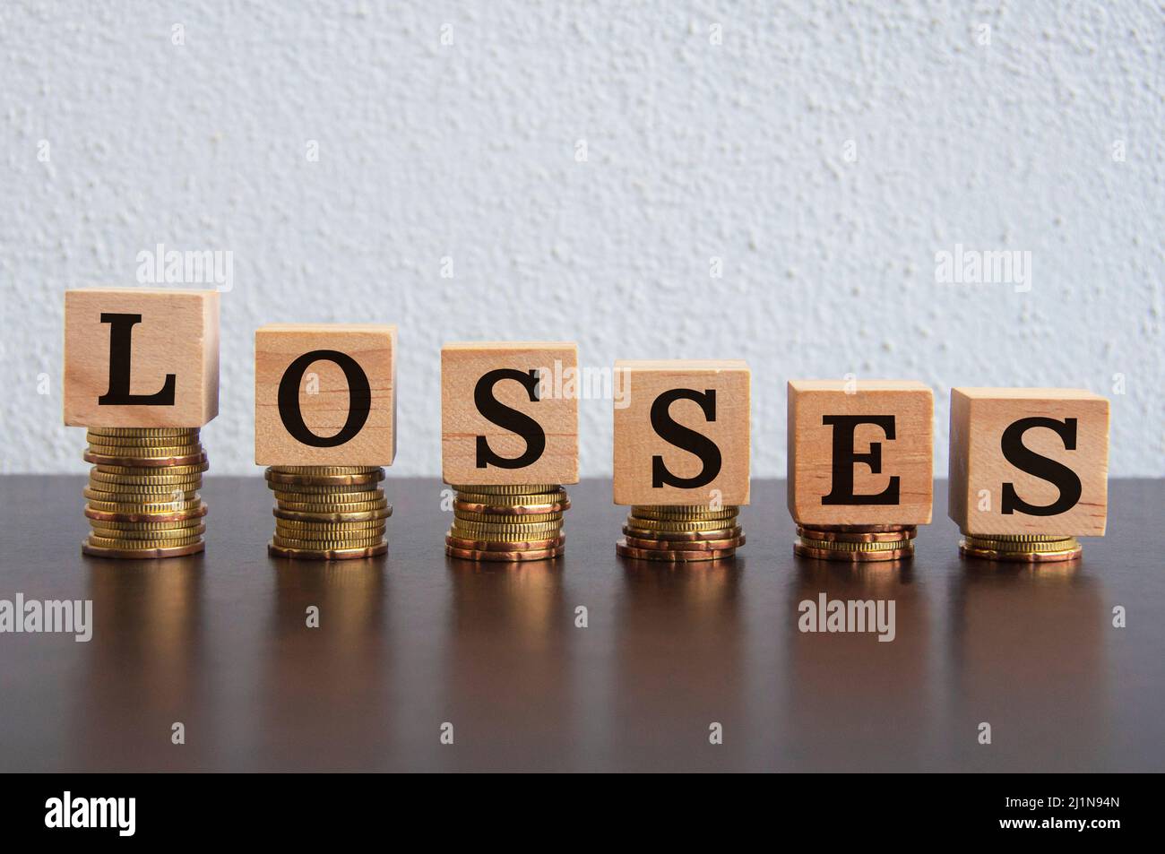 Monete impilate con testo delle perdite su blocchi di legno - Business e concetto finanziario Foto Stock