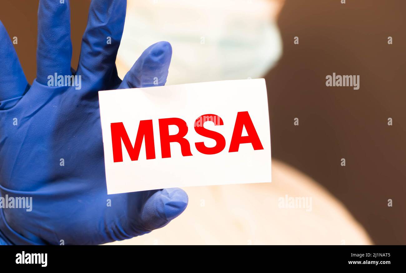 Le mani del medico in guanti blu mostra la parola MRSA resistente alla meticillina Staphylococcus aureus. Concetto medico. Foto Stock