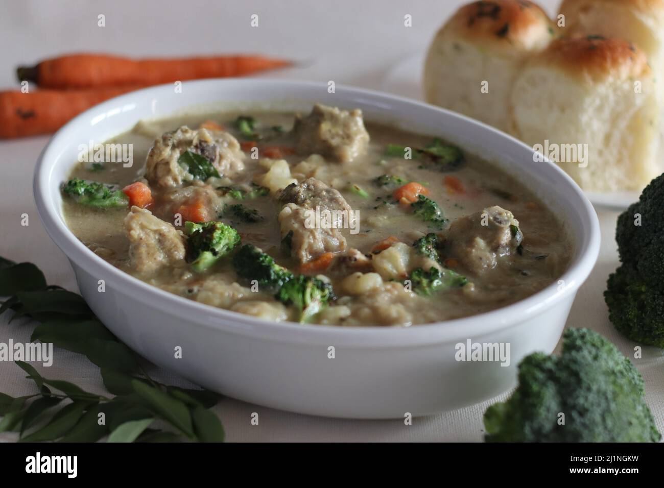 Pollo stufato con verdure. Preparazione in stile Kerala con carote, broccoli, patate, pollo, latte di cocco e spezie. Scatto su sfondo bianco Foto Stock