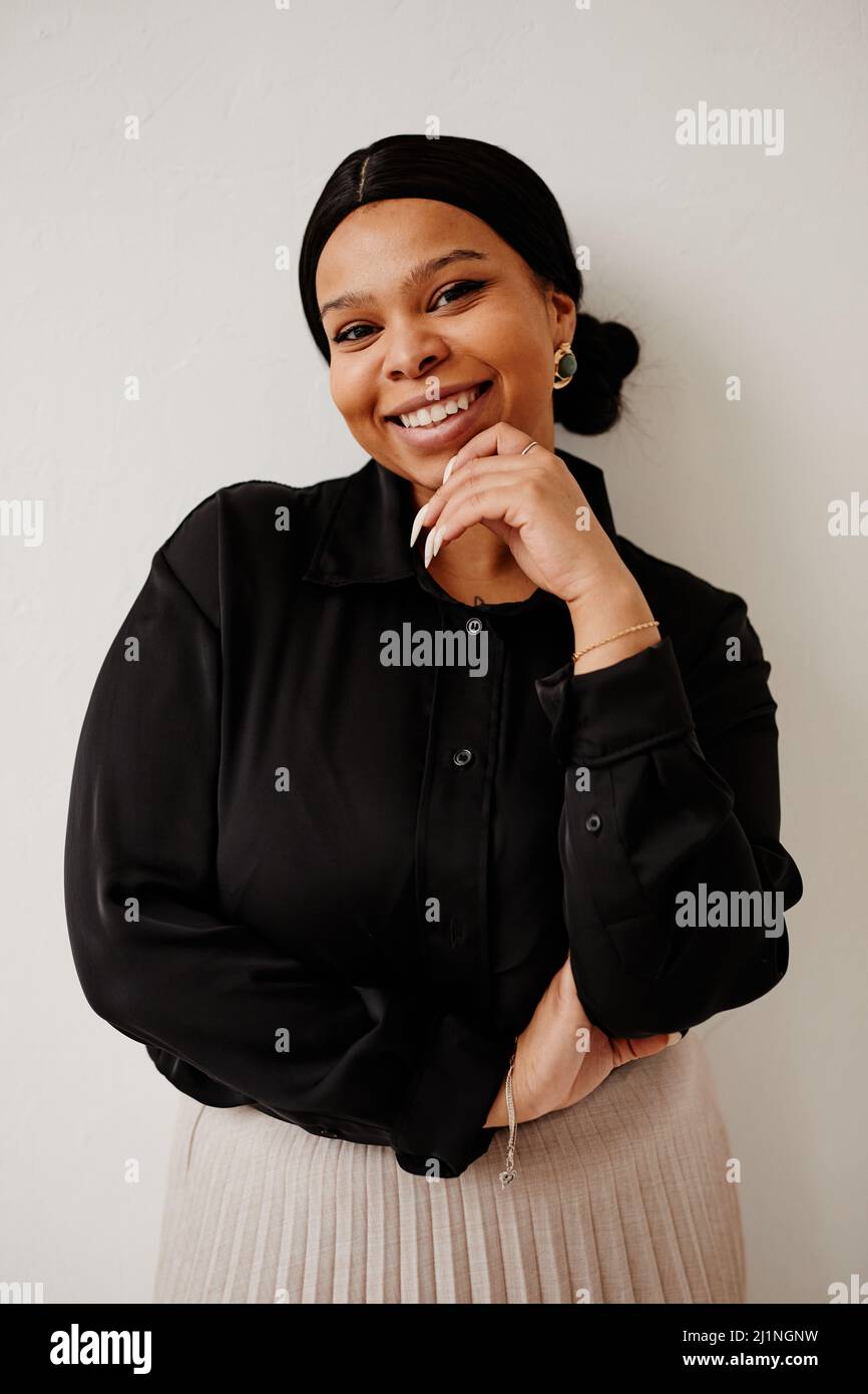 Ritratto minimal di donna nera elegante sorridente con gioia mentre si leva su sfondo neutro Foto Stock