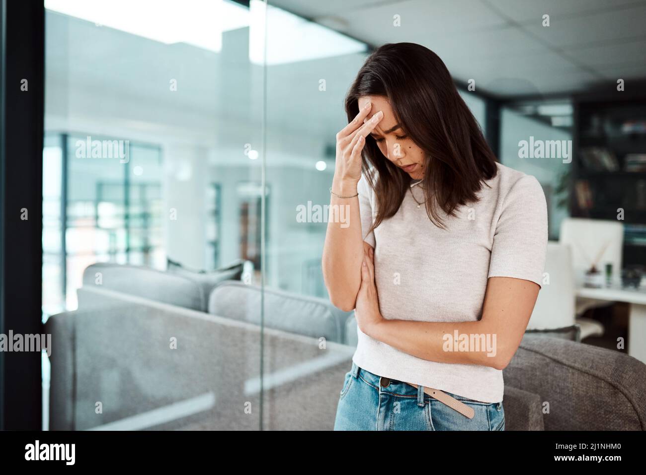 Lo stress sul posto di lavoro è un fattore di rischio importante per l'ansia e la depressione. Shot di una giovane donna d'affari che guarda stressata fuori in un ufficio. Foto Stock