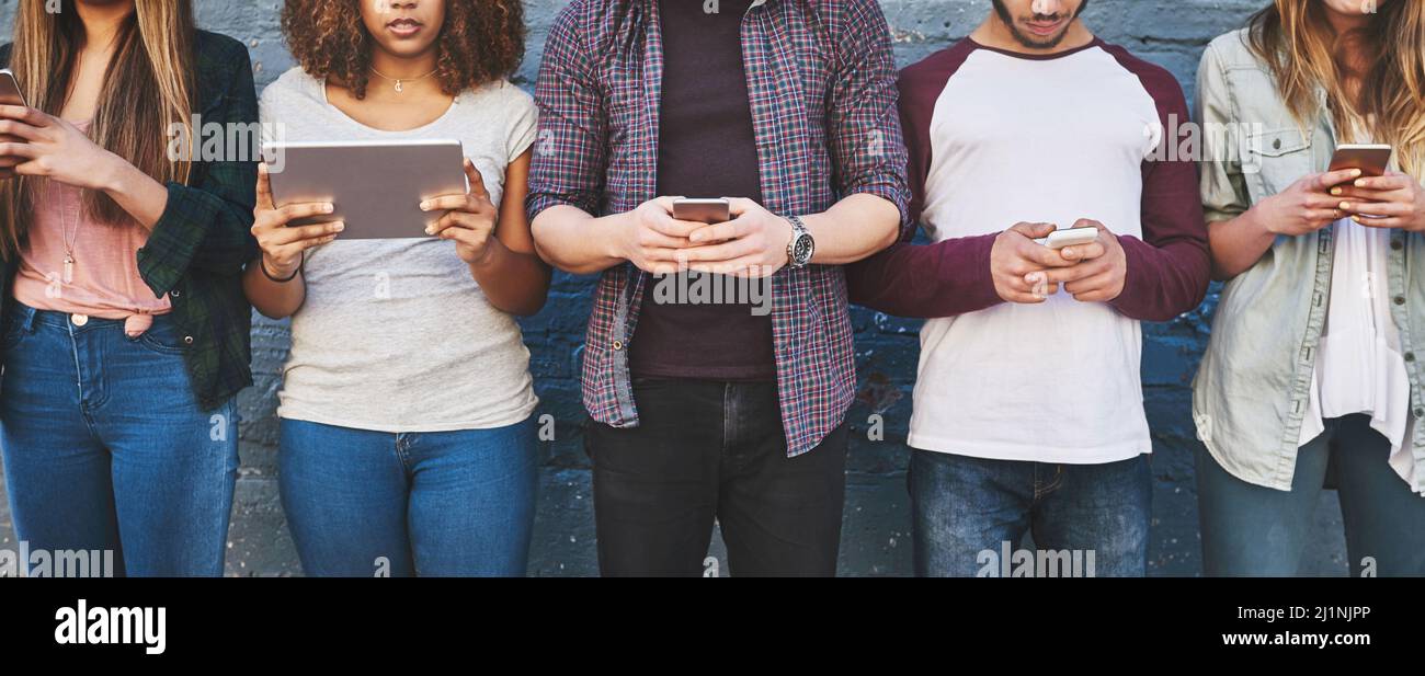 La rivoluzione digitale è ora. Foto di un gruppo di giovani amici che utilizzano i loro dispositivi wireless all'aperto. Foto Stock