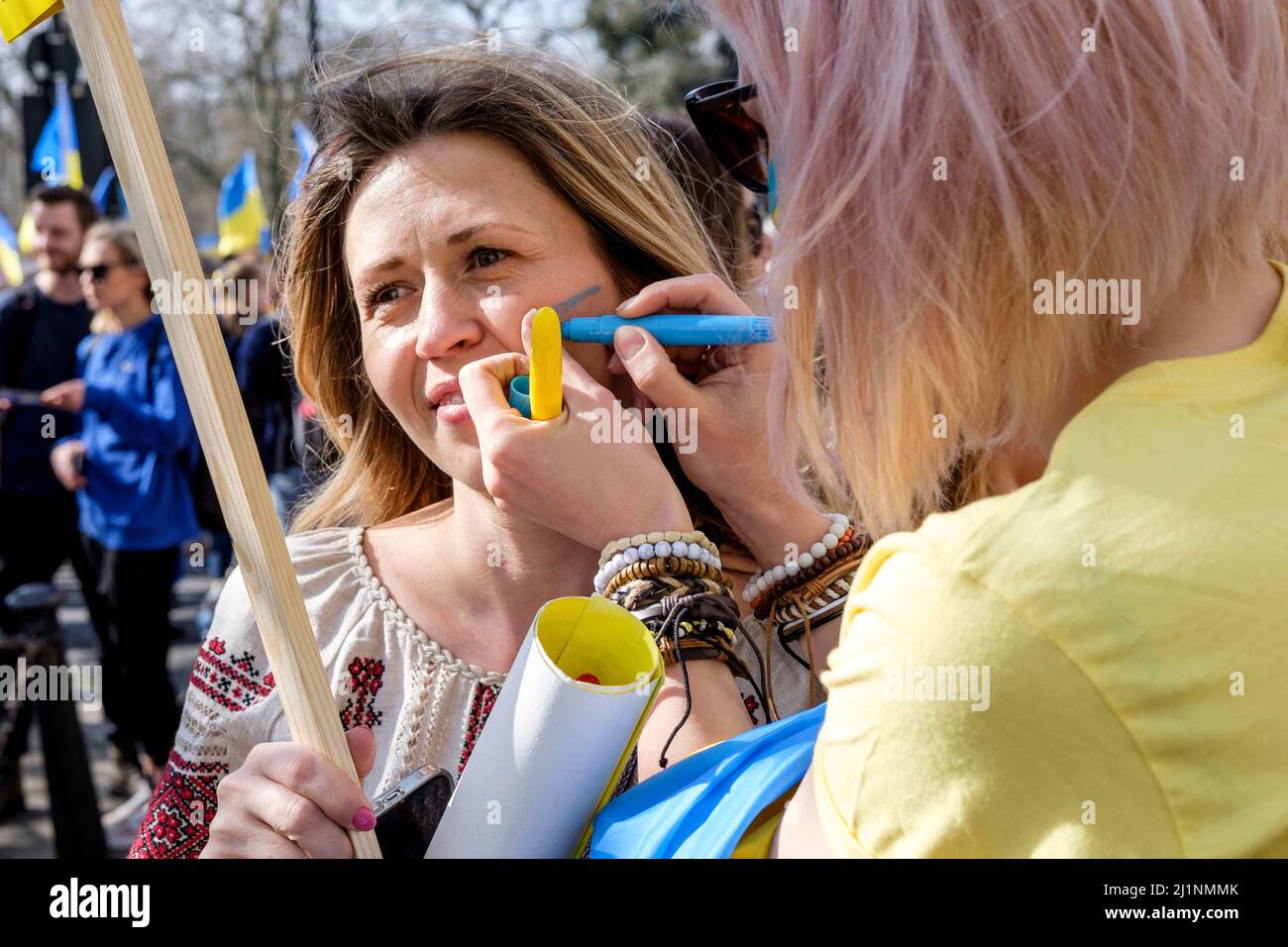 Londra UK, 26th marzo 2022. Migliaia di persone si uniranno a una marcia con l'Ucraina e si videranno nel centro di Londra per protestare contro l'invasione russa. Le donne ucraine dipingono i simboli della bandiera Ucraina sulle loro guance prima che inizi la marcia. Foto Stock