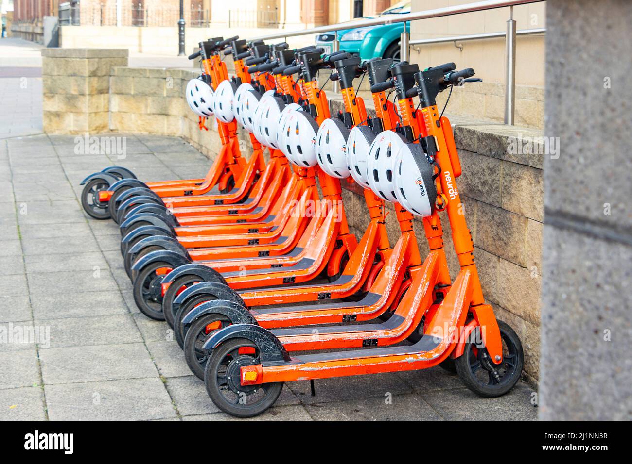 Orange neurone mobilità e scooter a noleggio parcheggiati in una fila a Newcastle su Tyne, Regno Unito Foto Stock
